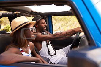 Couple Driving Open Top Car On Country Road