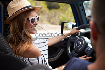 Young Couple Driving Open Top Car On Country Road