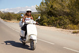 Young Woman Riding Motor Scooter On Country Road