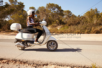 Young Woman Riding Motor Scooter On Country Road