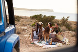 Group Of Friends Enjoying Picnic On Cliffs By Sea