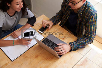 Teen couple study using laptop and phones, elevated close up