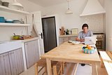 Teenage boy wearing headphones using technology in a kitchen