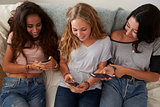Three teenage girls using smartphones at home, high angle