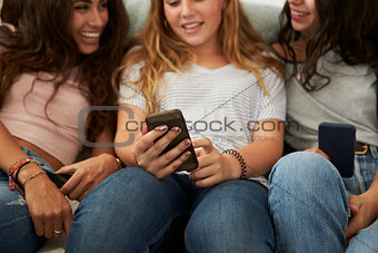 Teenage girl showing her friends   something on smartphone