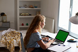 Teenage girl using laptop computer at a desk in her bedroom