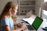 Teenage girl using laptop at a desk in her bedroom, close up