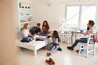 View from doorway of teenage friends hanging out in bedroom