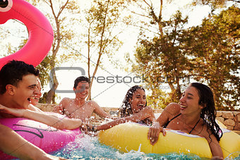 Teenage friends have fun with inflatables in a swimming pool