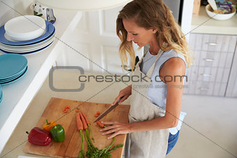Woman standing in kitchen chopping vegetables, elevated view