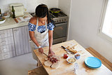 Elevated view of woman chopping ingredients at kitchen table
