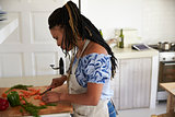 Woman standing in kitchen chopping vegetables