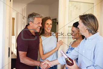 Couple greeting their guests at the door of their home