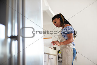 Low angle view of woman reading a recipe book and cooking