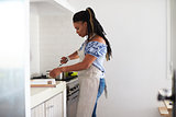 Woman cooking with a saucepan on the hob in her kitchen