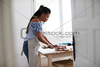 View from doorway of woman chopping food on kitchen table