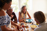 Friends talking at kitchen table while woman prepares food