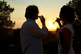 Adult couple drinking on a rooftop admiring the sunset