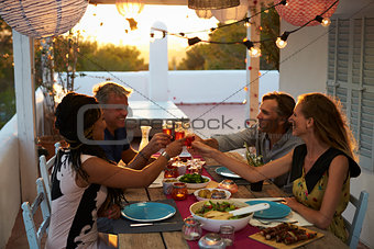 Two couples making a toast at dinner on a rooftop terrace