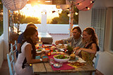Two couples eating dinner at a table on a rooftop terrace