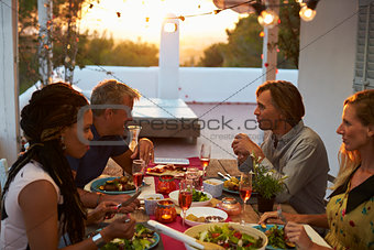 Two couples eating dinner on a roof terrace, close up