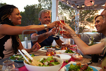 Couples make a toast at dinner on a roof terrace, close up