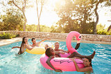 Group Of Friends On Vacation Relaxing In Outdoor Pool