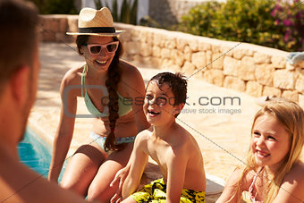Family On Vacation Relaxing By Outdoor Pool