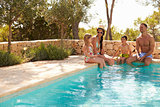 Wide Angle View Of Family On Vacation Relaxing By Pool
