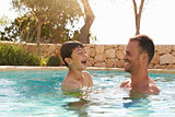 Father And Son On Vacation Having Fun In Outdoor Pool