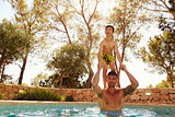 Son Jumping From Father's Shoulders In Outdoor Pool