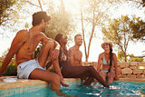 Group Of Friends On Vacation Relaxing Next To Outdoor Pool