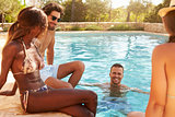 Group Of Friends On Vacation Relaxing Next To Outdoor Pool