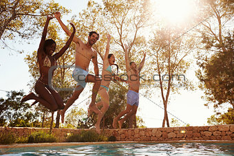 Group Of Friends On Vacation Jumping Into Outdoor Pool