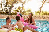 Family On Vacation On Inflatables In Outdoor Swimming Pool