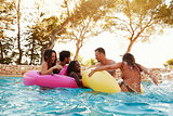Group Of Friends On Inflatables In Outdoor Pool