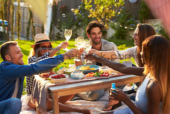 Group Of Friends Enjoying Outdoor Picnic In Garden