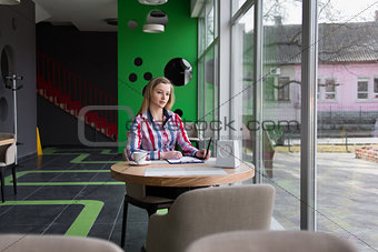 girl with pen in hand sitting in a cafe