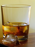 glass of whiskey with ice on a gold background