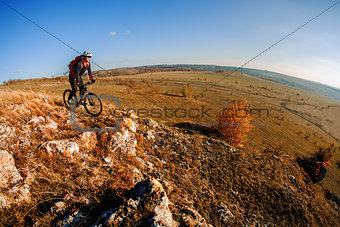 Wide angle view of a cyclist riding a bike on a nature trail in the mountains.