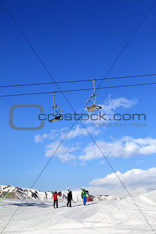 Three skiers on slope at sun winter day