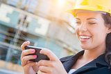Female Contractor Wearing Hard Hat on Site Texting with Cell Pho