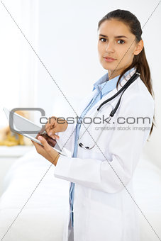 Young brunette female doctor standing and smiling at hospital