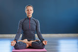 Beautiful young woman sitting in Lotos pose. woman practicing meditation in yoga hall after hard day.