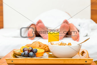 couple in bed, a tray of food in focus