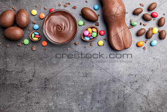 Chocolate Easter bunny, eggs and sweets on rustic background