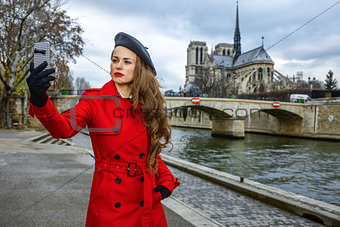 woman taking selfie with phone near Notre Dame de Paris in Paris