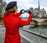 traveller woman on embankment in Paris taking photo with phone