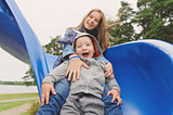 Smiling girl and boy having fun on children's slide