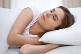 Beautiful young and happy woman sleeping while lying in bed comfortably and blissfully smiling